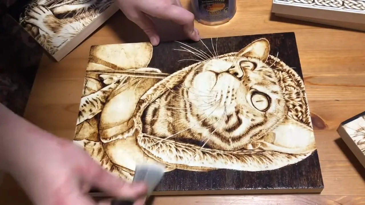 Brushing a clear finish onto a completed wood-burned cat design