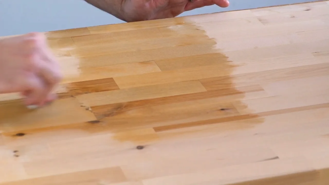 A cloth spreading finish across wood, showing the color change between coated and uncoated areas