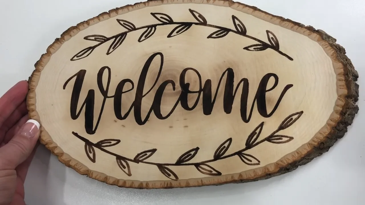 Live-edge oval welcome sign with dark script lettering and a leaf border
