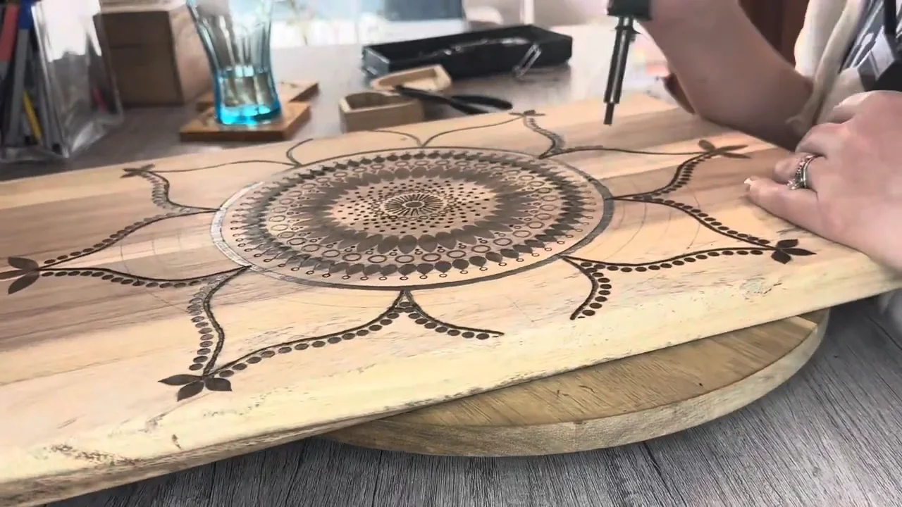 A wood-burned mandala with concentric rings of petals, circles and dots.