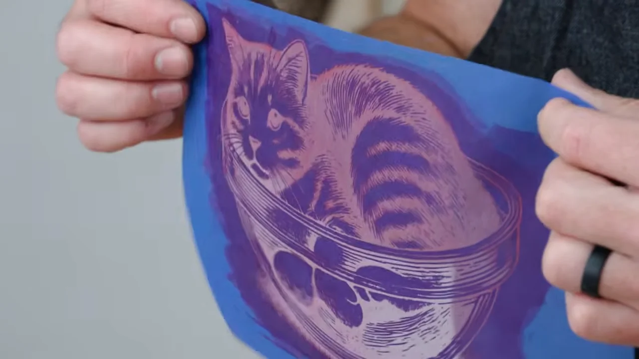 Hands holding a reusable mesh stencil with a detailed cat design after applying heat-activated paint