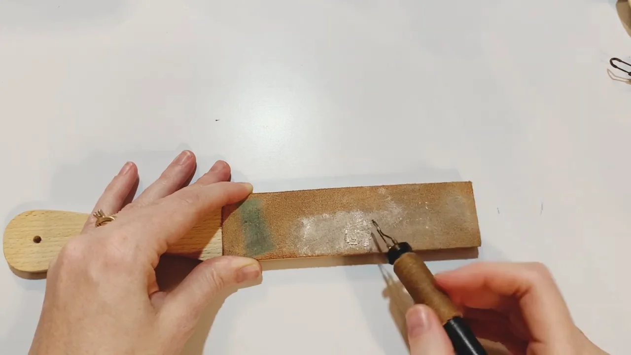 Pyrography pen positioned beside a leather cleaning strop